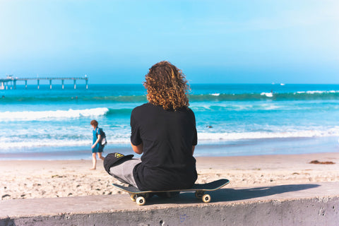 A person with curly hair facing the ocean