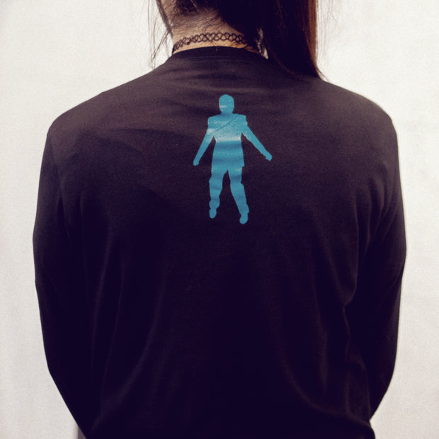 Back of black long sleeve shirt with a blue outline of a person's body in the top center. On both arms there is text and images in the same blue color. An individual is modeling the shirt and standing in front of a white wall.