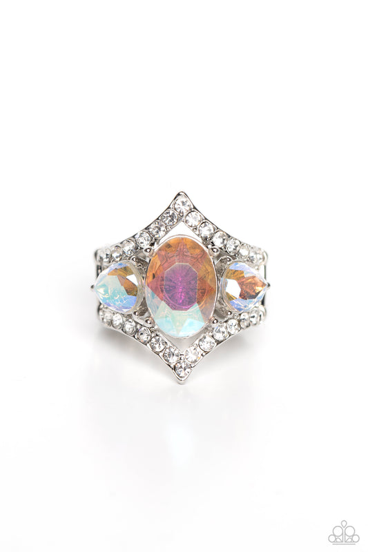 An oversized iridescent oval gem is flanked by a pair of iridescent teardrop rhinestones atop a white rhinestone dotted frame, resulting in a dramatic dazzle atop the finger. Features a stretchy band for a flexible fit. Due to its prismatic palette, color may vary.