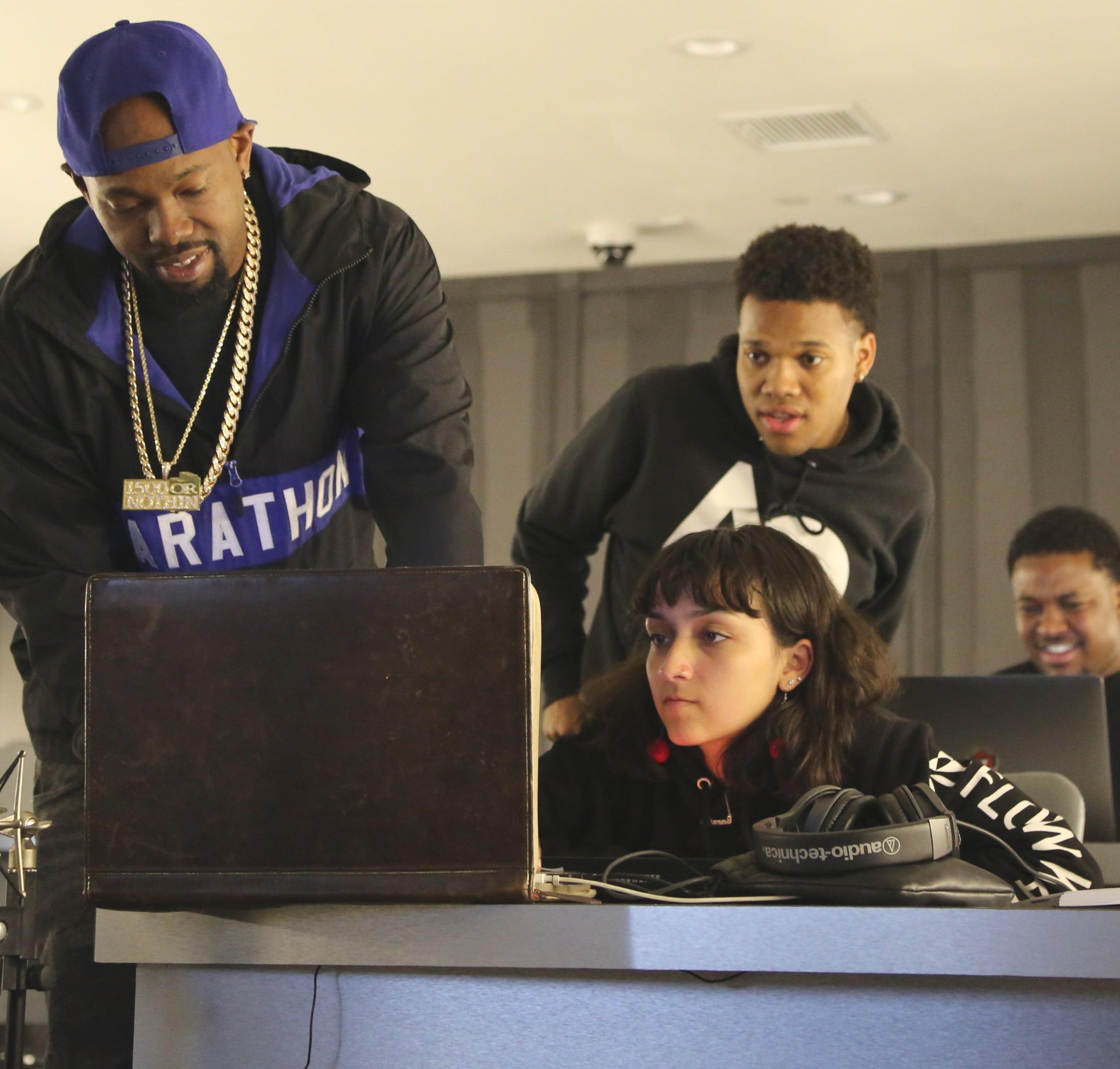 two students looking at a computer with a man standing showing them something on the computer