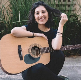 smiling girl sitting down with a guitar