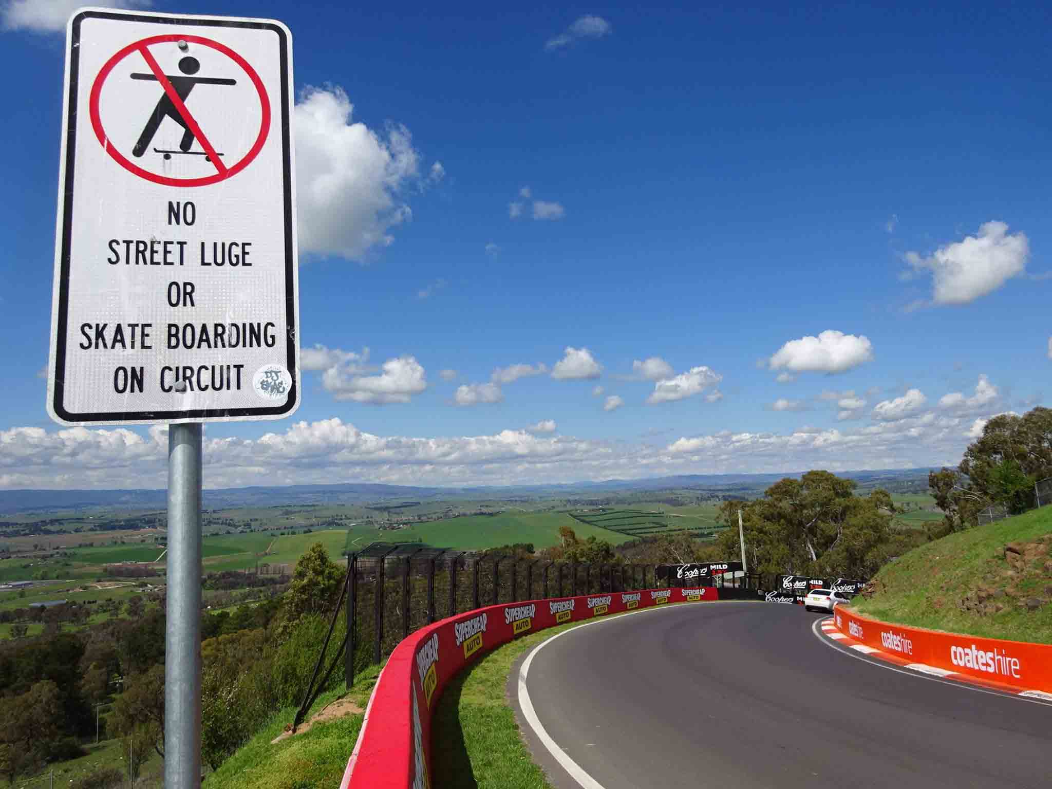 View of Bathurst Plains atop Mount Panorama Race Track at 'The Esses' corner Bathurst featuring sign reading "No street luge or skate boarding on circuit"