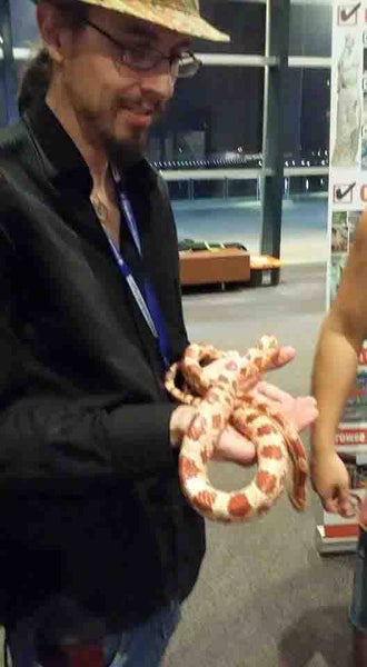 Kieran Wicks holding an Orange and White stripped snake in Darwin Crocodylus Park