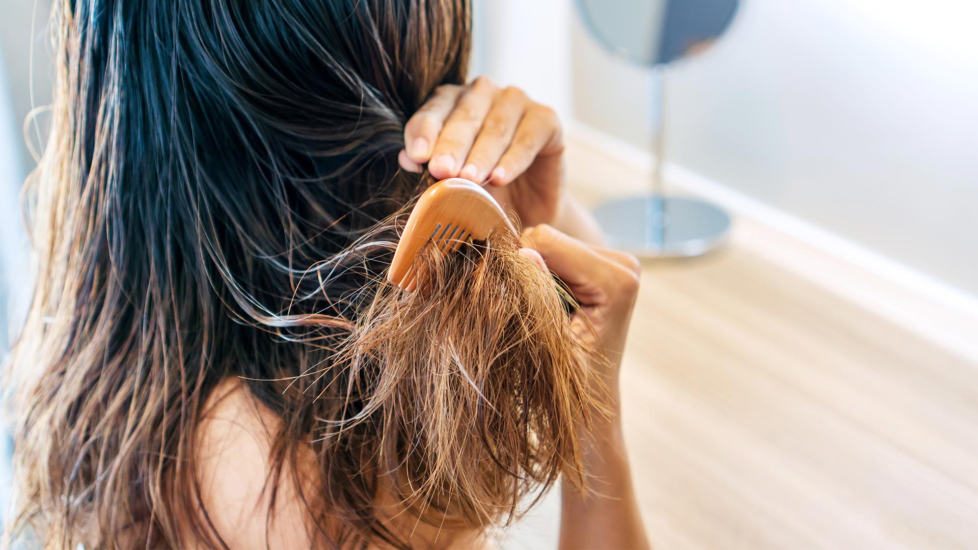 A woman brushing her damaged hair.