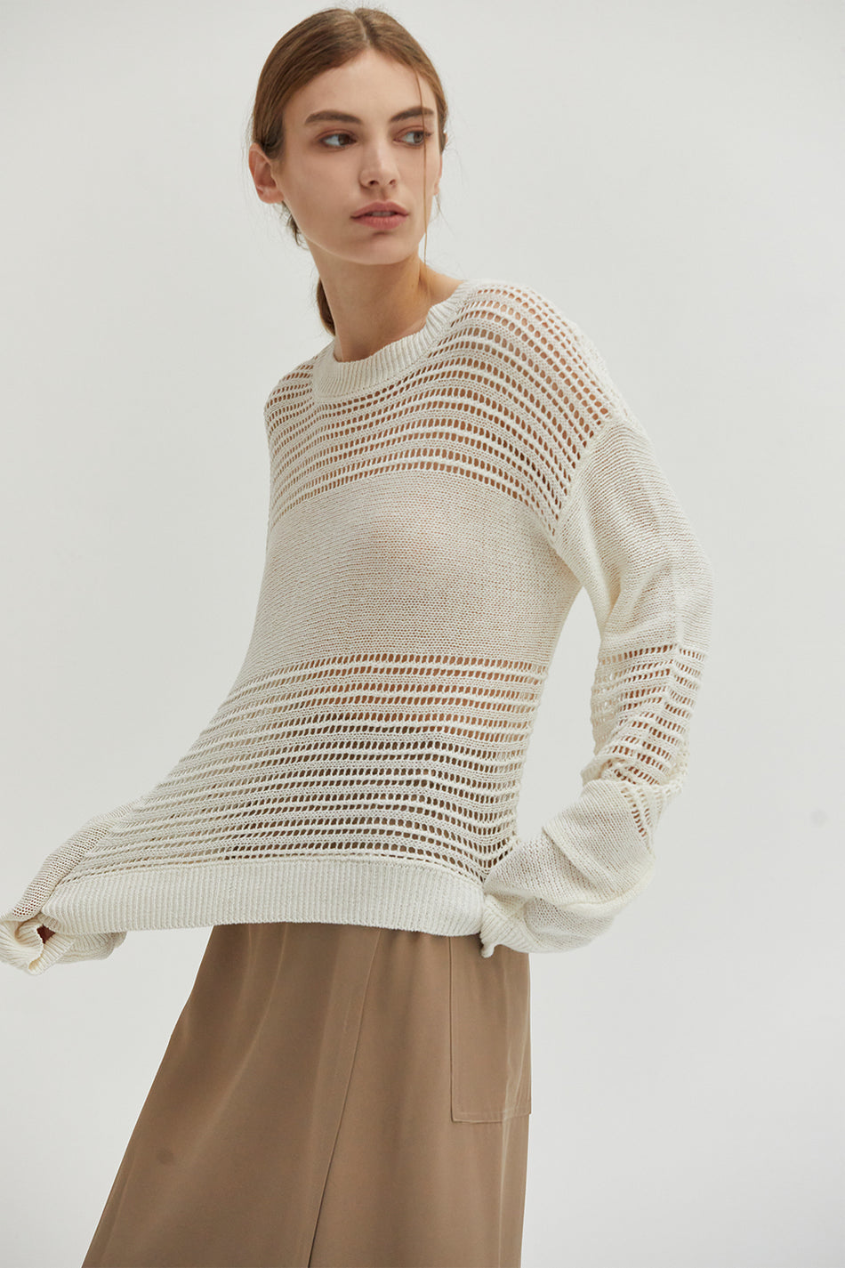 a studio model in a white knit sweater