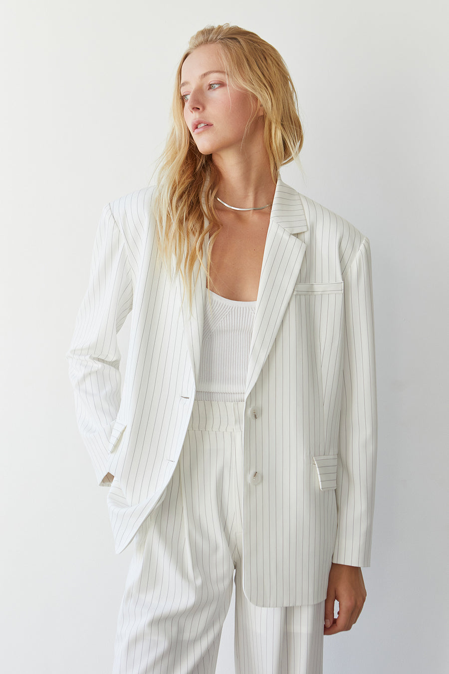a model wearing a white pinstripe blazer and pants