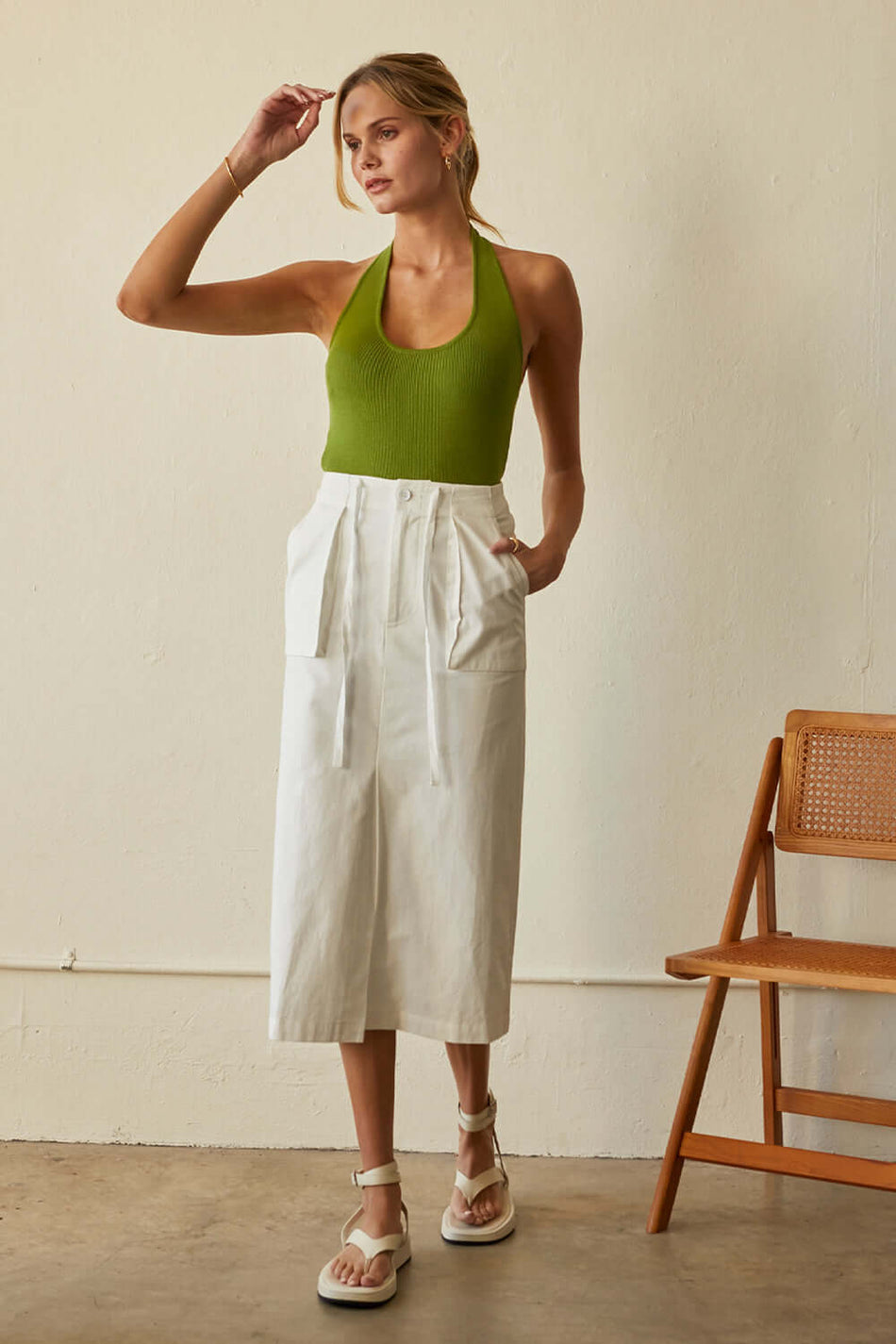 a model in a white midi skirt and a green top