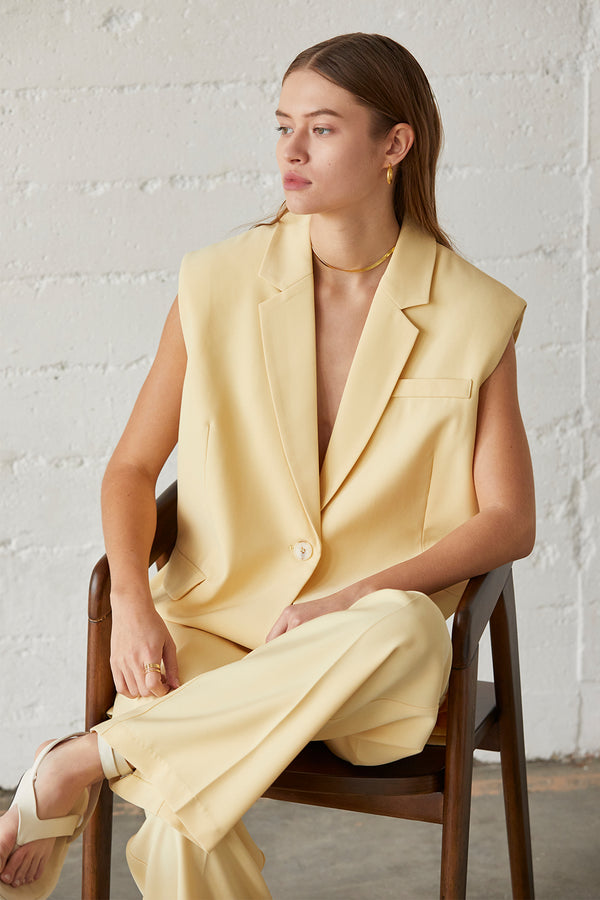 a model in a light yellow sleeveless suit set