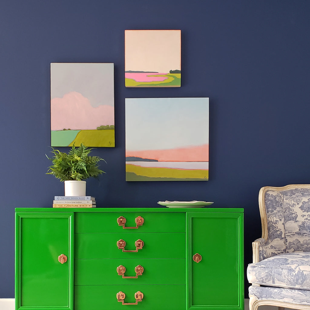 gallery wall with landscape paintings over buffet