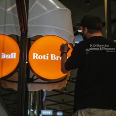 Orange Roti Bros sign being installed