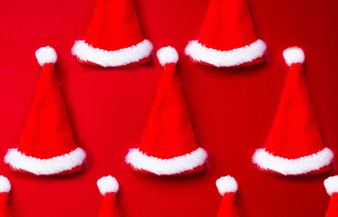 image of a few mini red Santa hats on a red background