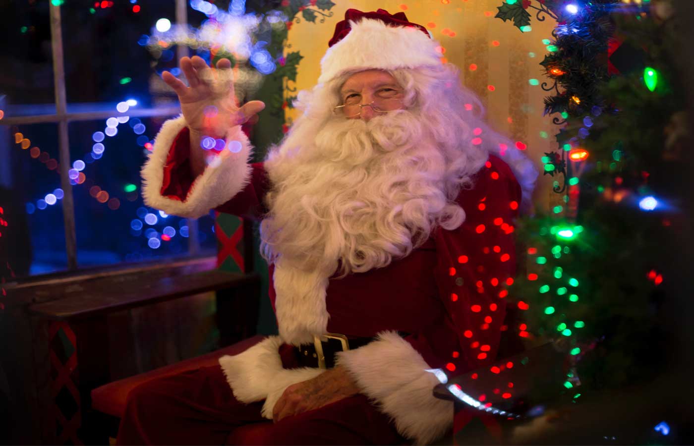 image of Santa Claus sitting down on a chair and waving