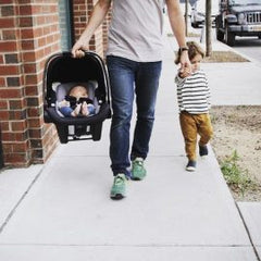 Dad holding a son's hand and a carseat