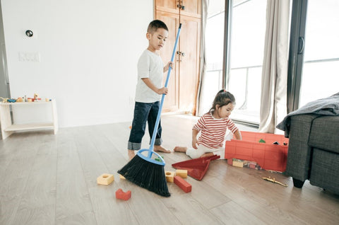 kid sweeping and putting away toys