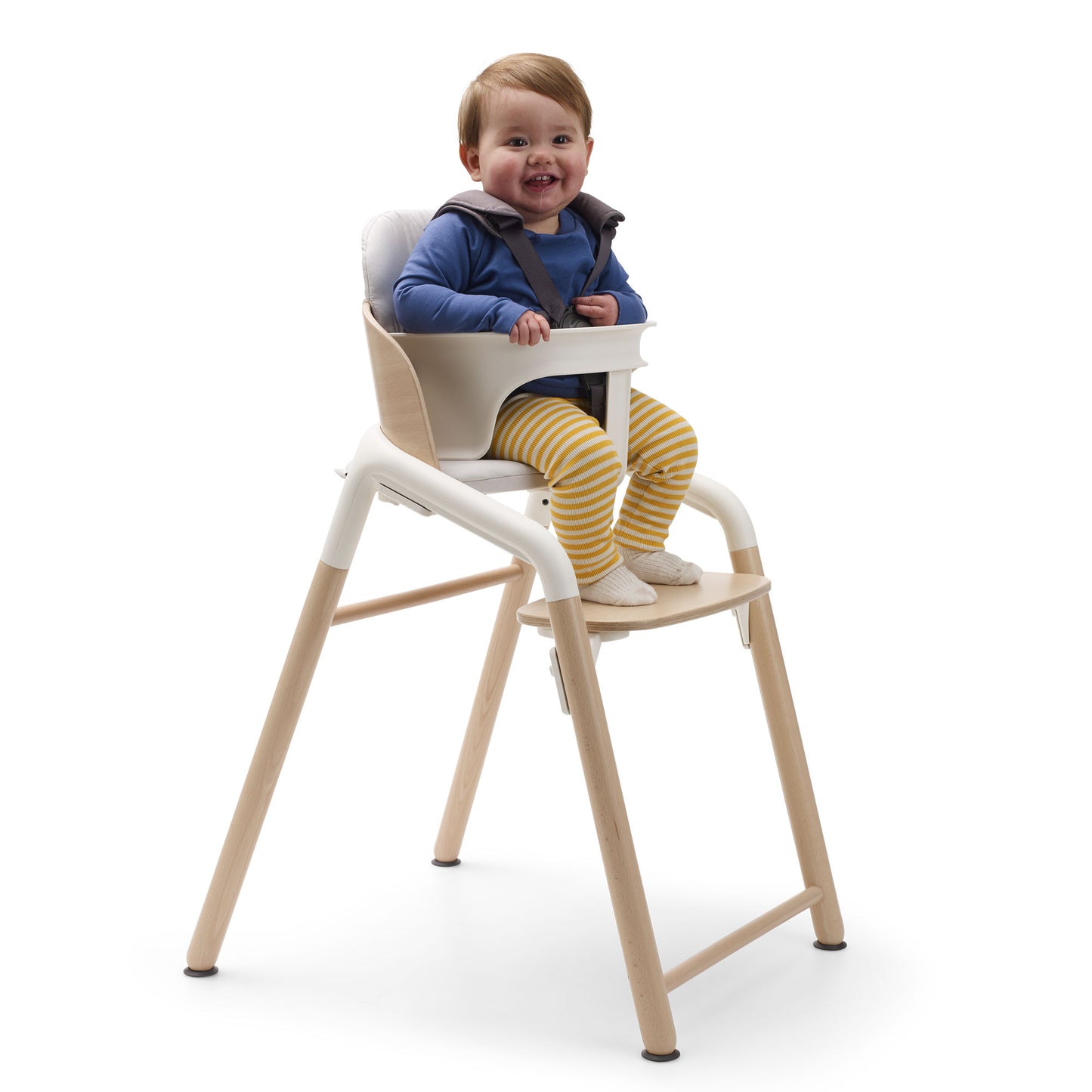 Baby sits in Bugaboo Giraffe High Chair Complete - Natural Wood/White