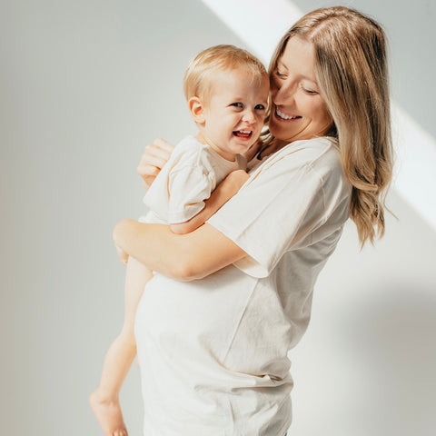 pregnant mother wearing organic everyday tee holding toddler son wearing organic everyday onesie