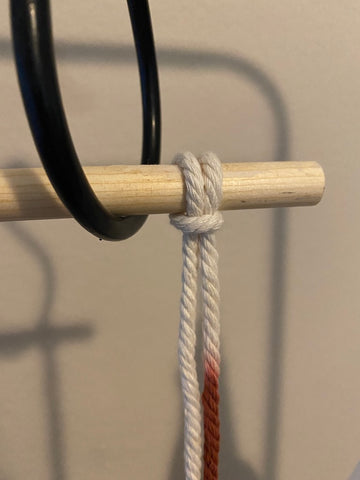 dyed macrame cord tied onto wooden dowel using Lark's head knot