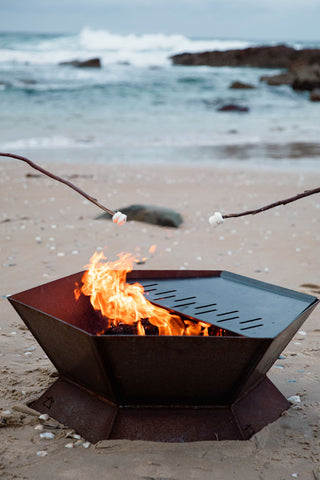 Firepit on the Tasmanian beach with sticks toasting mashmallows.