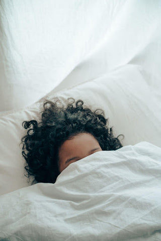  Woman sleeping with the white sheet over her face. 