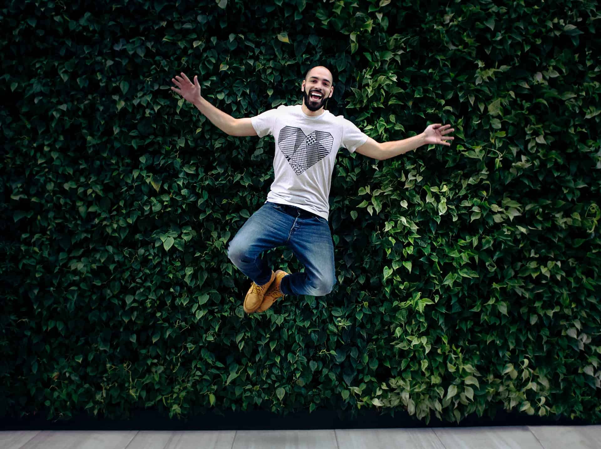 A man full of energy and jumping in front of leaves