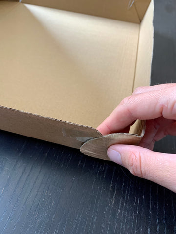 Attach cardboard box corners with tape for DIY shadow puppet theatre