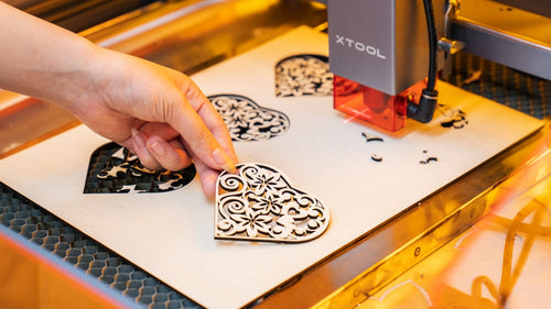 a laser cutter cutting a piece of wood into a heart shape