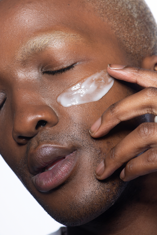 Model applying sunscreen on face | Standard Beauty