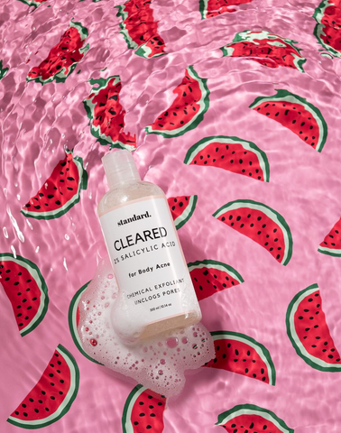 Body wash bottle floating in water with watermelon background | Standard Beauty