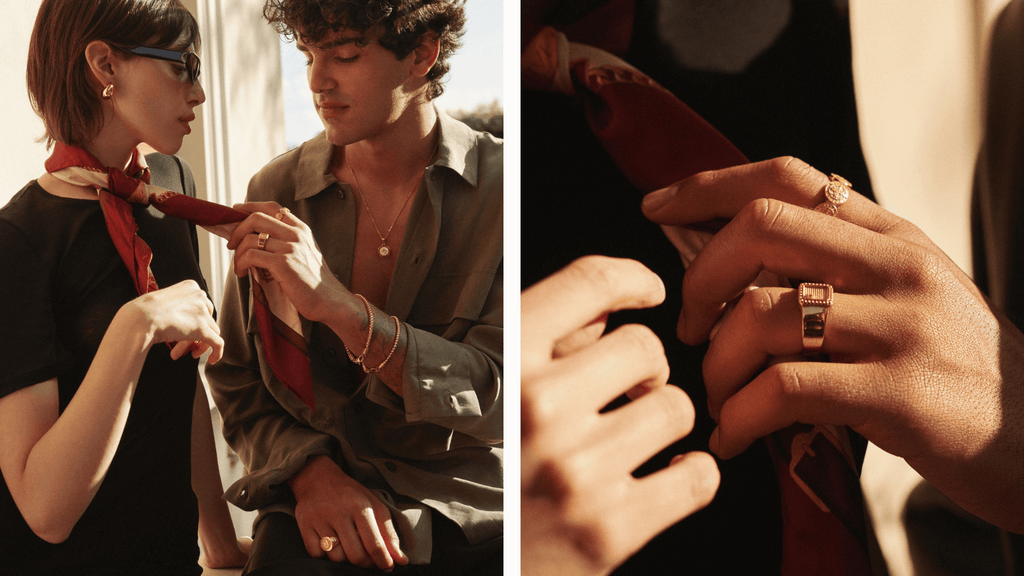 Man and women sat in the sun being romantic. Man is wearing different types of mens gold jewelry including a signet ring and band ring