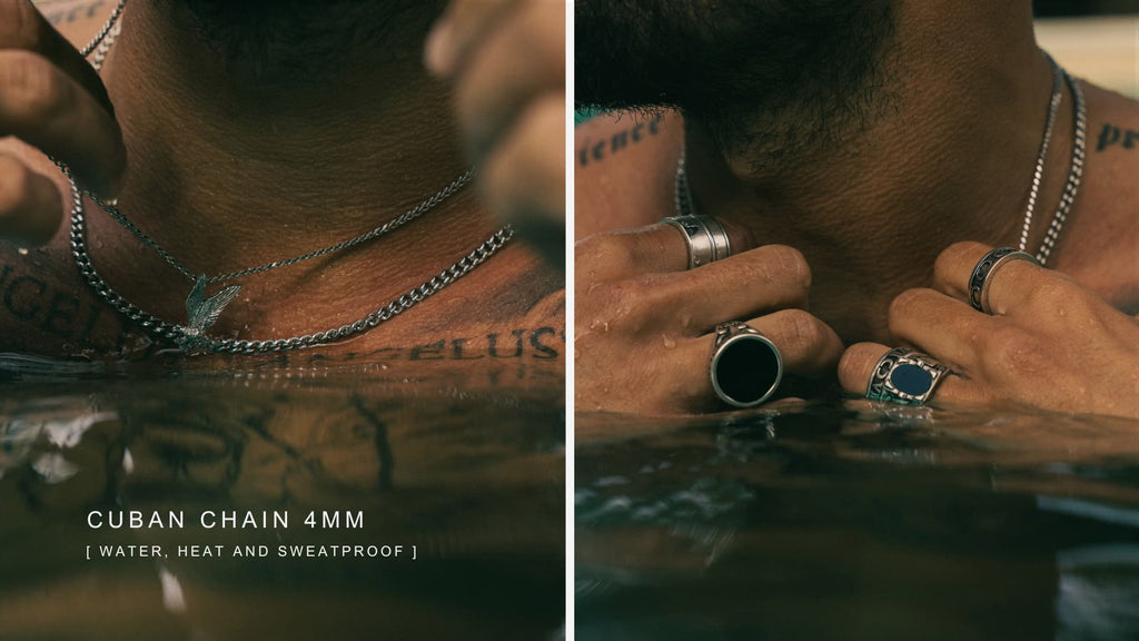 Man's chest in water with a thin cuban link chain dipped in the water with droplets falling off of it