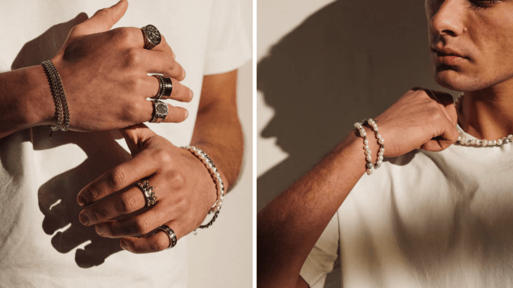 Man wearing a plain white t-shirt and wearing different men's silver accessories including signet rings and cuban link chains and bracelets