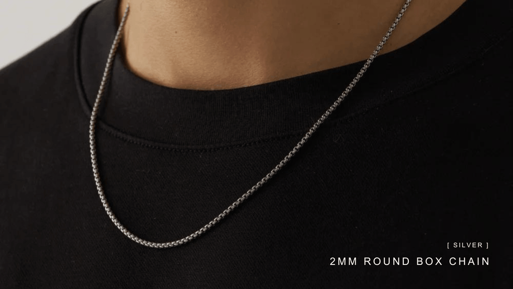 Man wearing a plain black t-shirt and accessorising with a sleek silver box chain