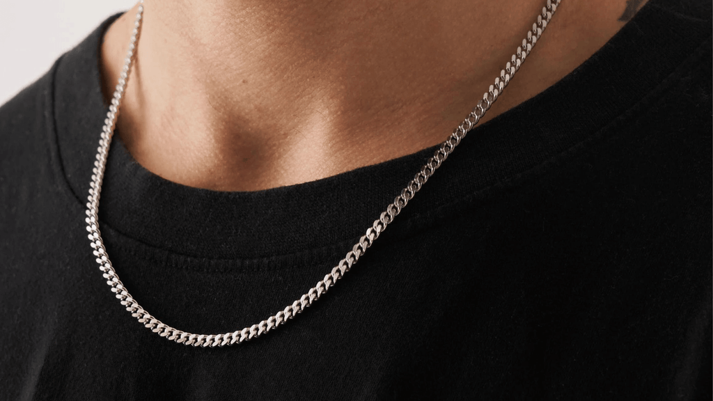 Man wearing a plain black top and a sterling silver cuban link chain