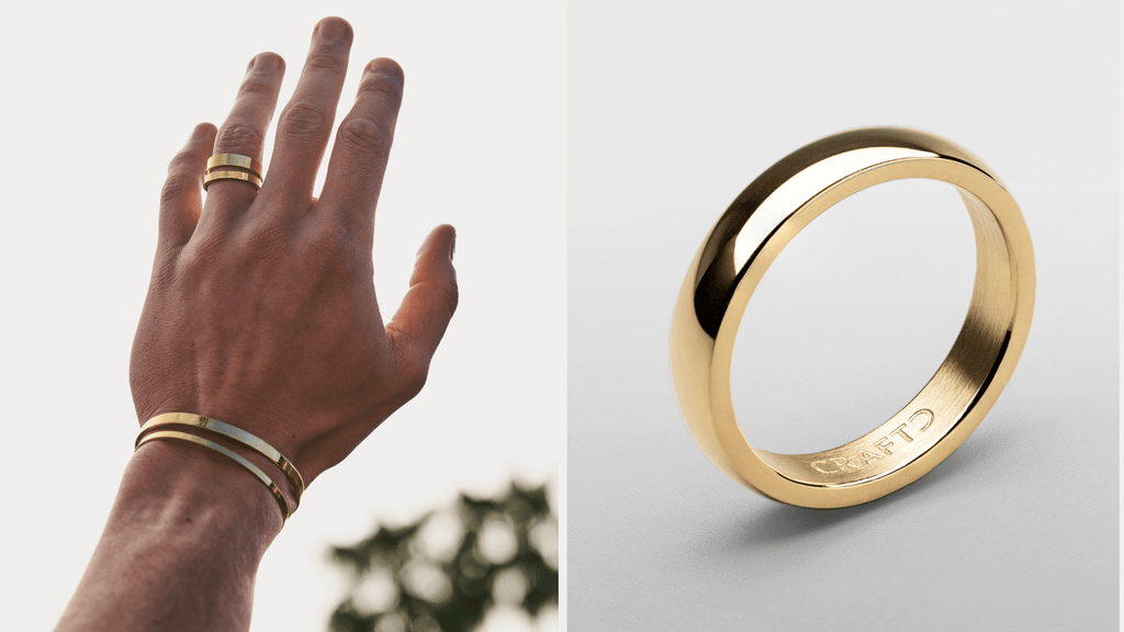 Man's hand reaching up into the sky styling a sleek gold band ring with the light reflecting off of it