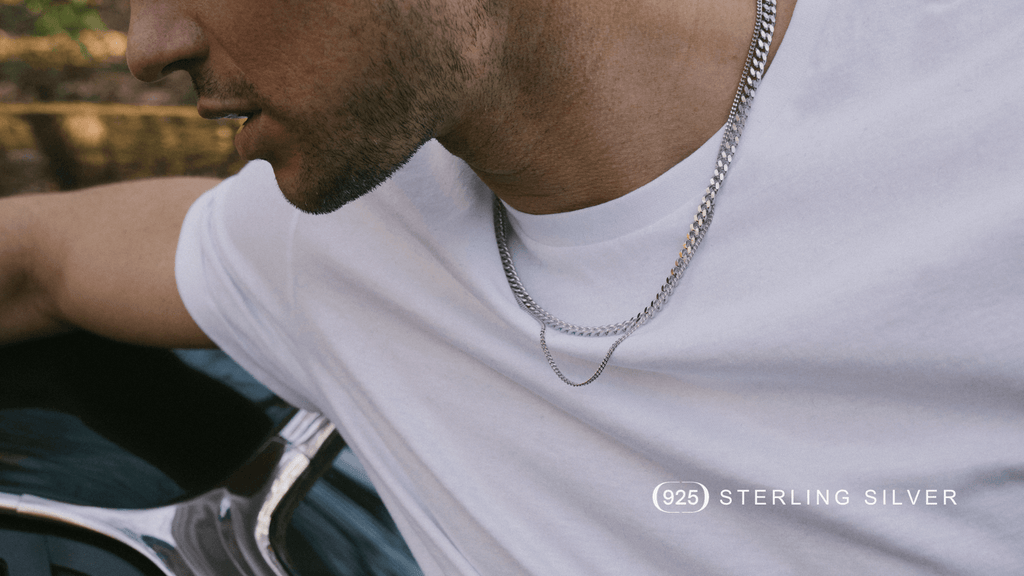 Man in a plain white t-shirt leaning on a car and wearing a Sterling Silver Cuban Link Chain