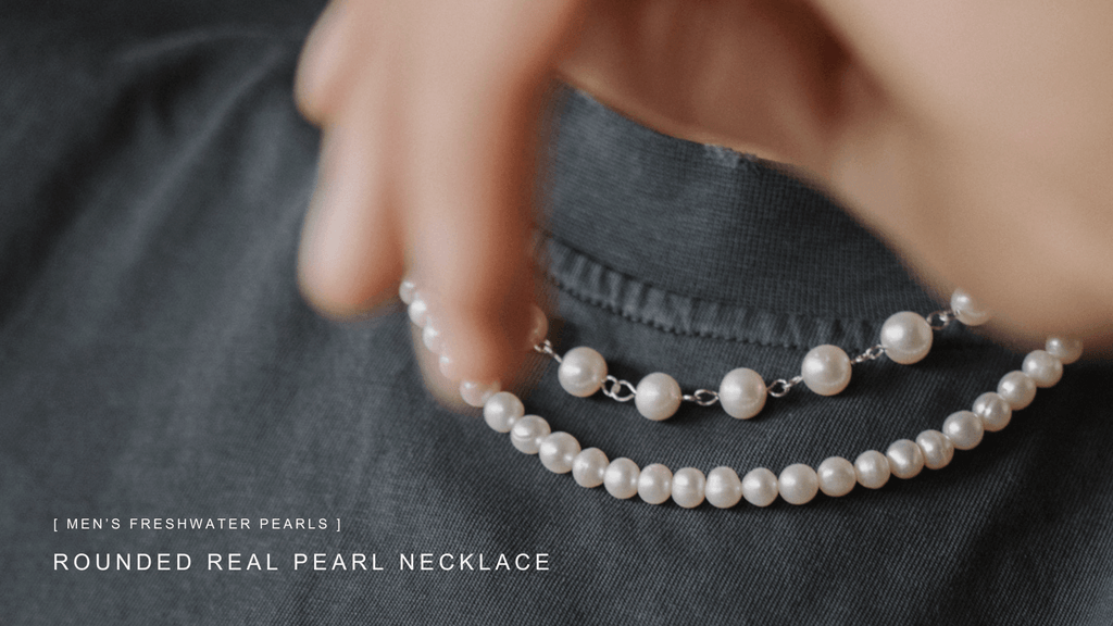 Close up of a deep charcoal coloured t-shirt with a pair of contrasting white set of men's freshwater pearl necklaces