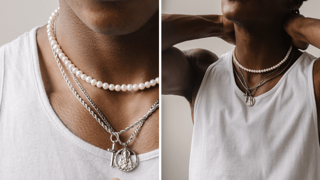 Man in a white vest top wearing a pearl necklace and two silver pendants