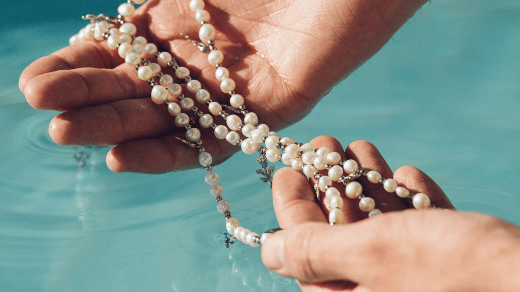 Man holding a set of mens pearl necklaces under the water to show they are durable