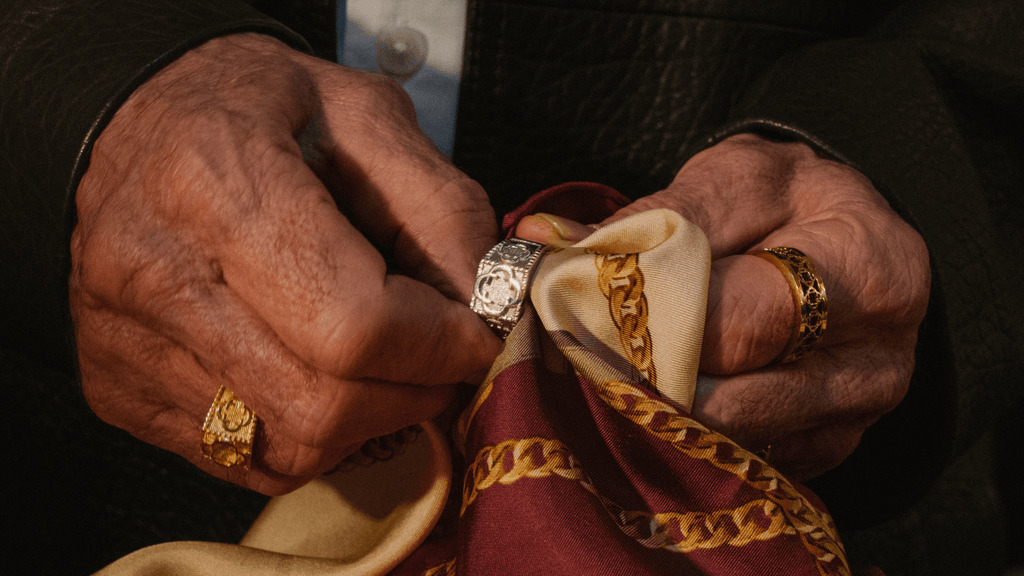 Man's hands polishing an assortment of men's gold and silver signet rings