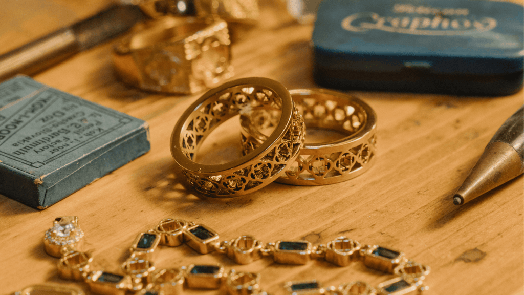Two Men's 18K Gold band rings stacked on top of a desk