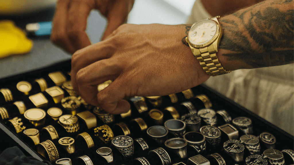 Man's hand sorting through his large gold and silver ring collection including band rings and signet rings