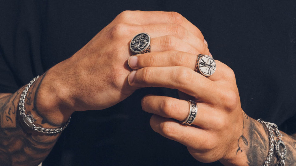 Man hands wearing a silver Cuban Link Bracelet and matching signet rings