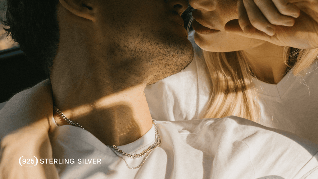 Man leans it to kiss girl. An unclose shot reveals the allure of his premium Sterling Silver Jewellery