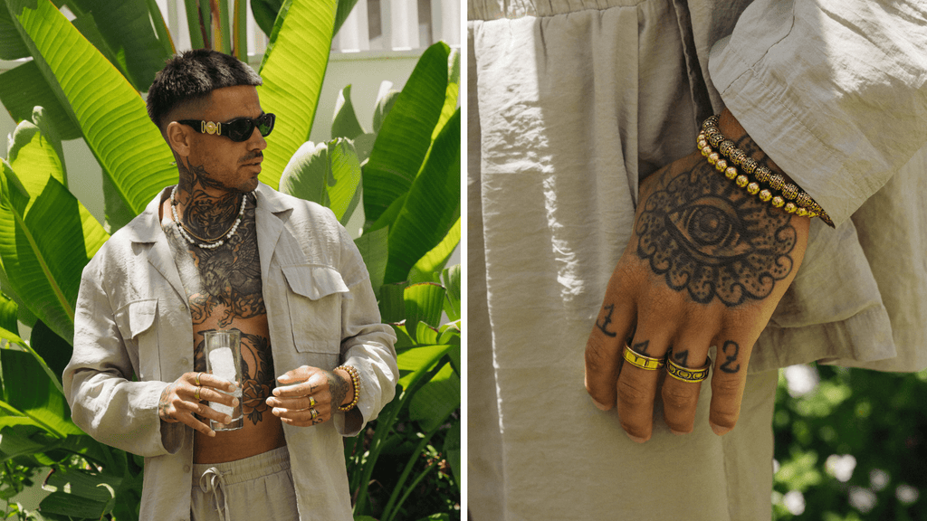 Man in a summer shirt and outfit wearing a mens pearl necklace and other gold necklaces and rings