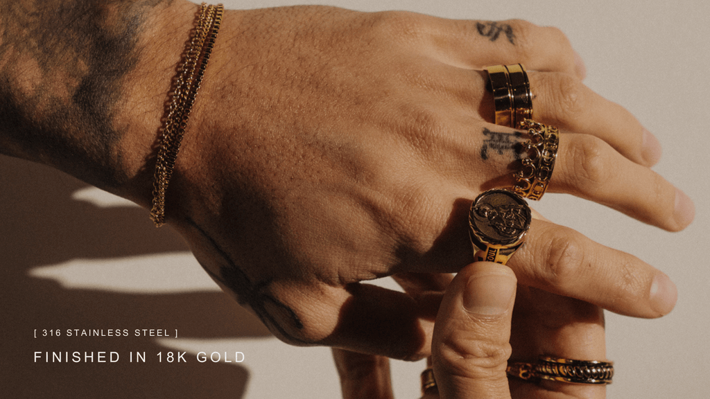 Up close shot on man's hand wearing multiple 18K gold band rings and signet rings