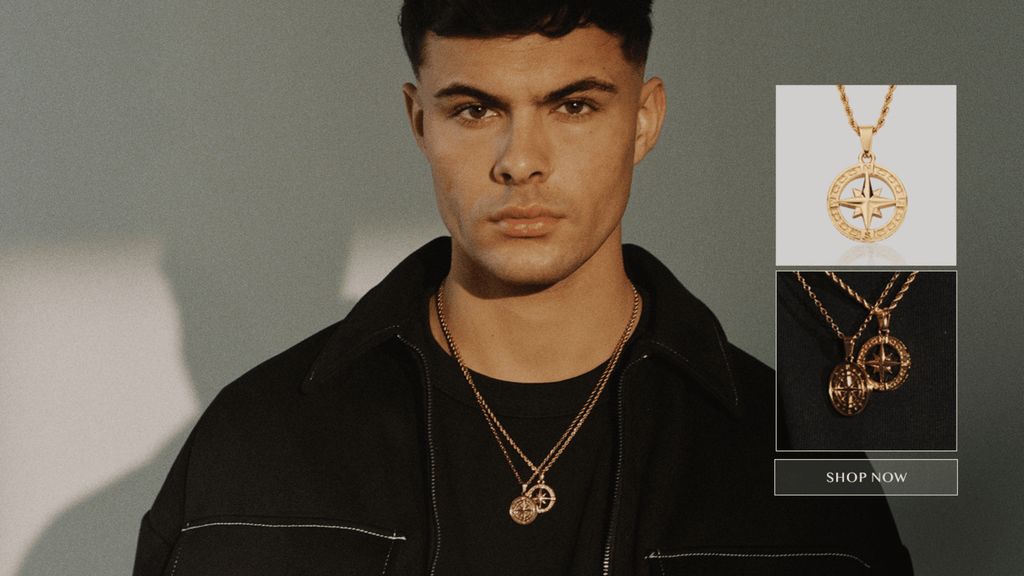 Medium shot of a man facing the camera. He's wearing jet black clothes and accessorising 18K Gold men's necklaces and pendants