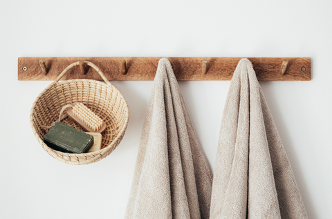 Wooden rack holding towels and a basket with bars of soap inside.