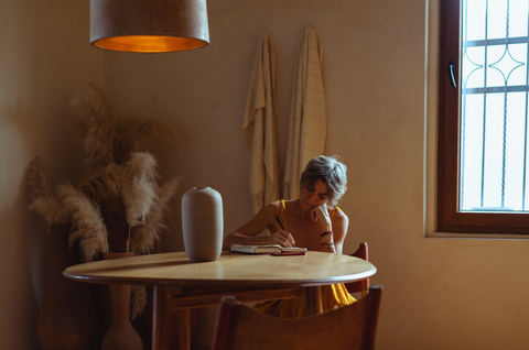 Woman sitting at desk writing in journal.