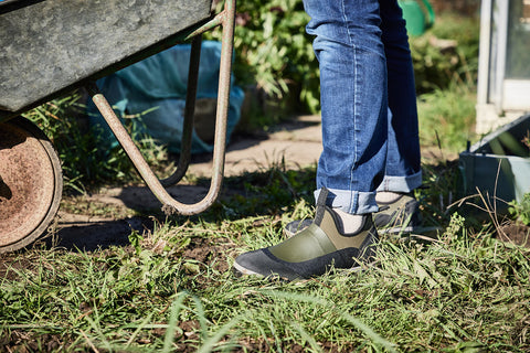 Lamb gardening boots worn on allotment whilst pushing wheelbarrow
