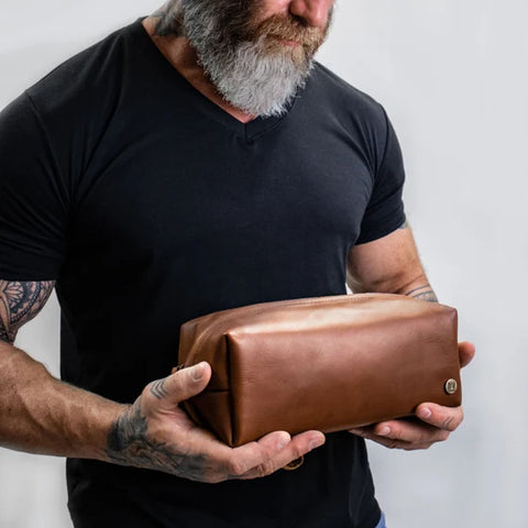 man holding a leather toiletry bag